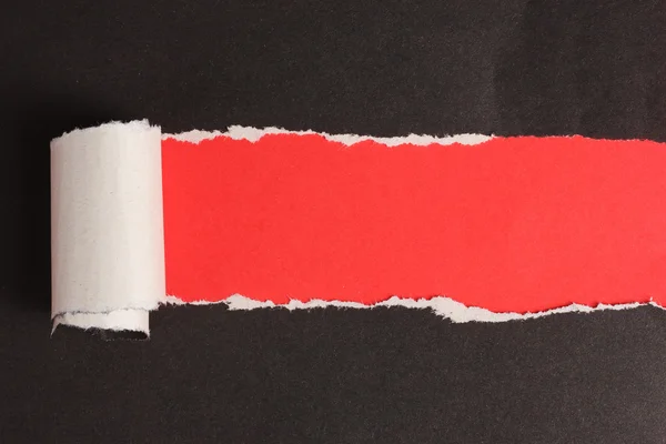 Порванная черная бумага с красным фоном — стоковое фото