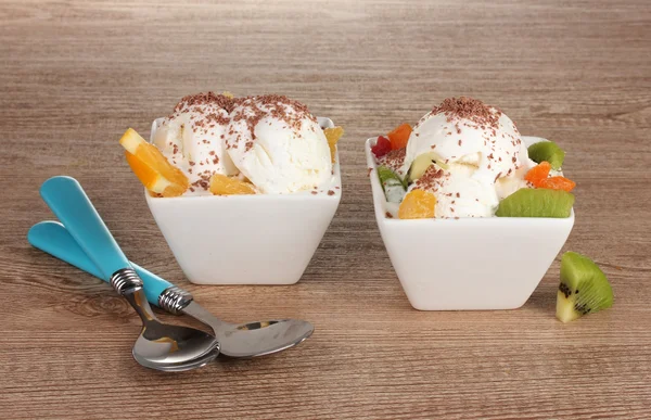 Läcker vaniljglass med choklad och frukt i skålar och skedar o — Stockfoto