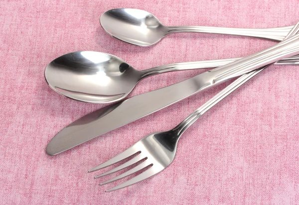 Forchetta, cucchiaio e coltello su una tovaglia rosa — Foto Stock