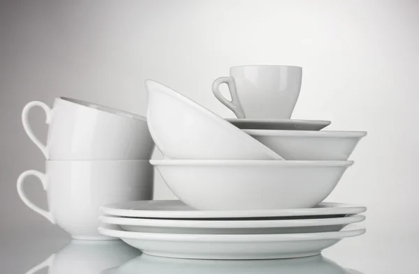 Üres tálak, tányérok és csészék, szürke háttér — Stock Fotó