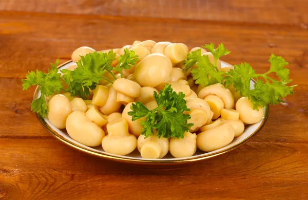 Funghi marinati in piattino su tavolo di legno — Foto Stock