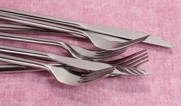 Garfos e facas em uma toalha de mesa rosa — Fotografia de Stock
