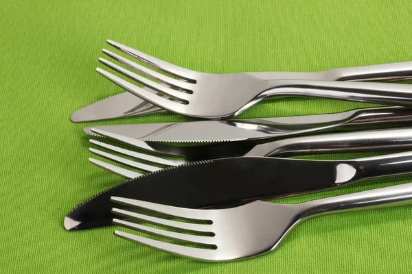 Tenedores y cuchillos en un primer plano de mantel verde — Foto de Stock