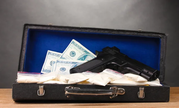 Cocaine, dollars and handgun in case on wooden table on grey background — Stock Photo, Image