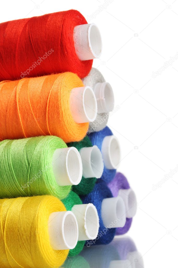 Pyramid of many-coloured bobbins of thread isolated on white
