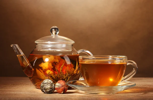 Glas theepot en cup met exotische groene thee op houten tafel op bruine backgro — Stockfoto