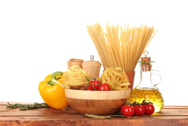 Spaghetti, makaron w misce, słoik oleju i warzywa na drewnianym stole isola — Zdjęcie stockowe