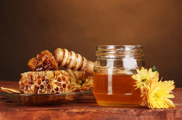 Pot met honing, honingraten en houten drizzler op tafel op gele achtergrond — Stockfoto