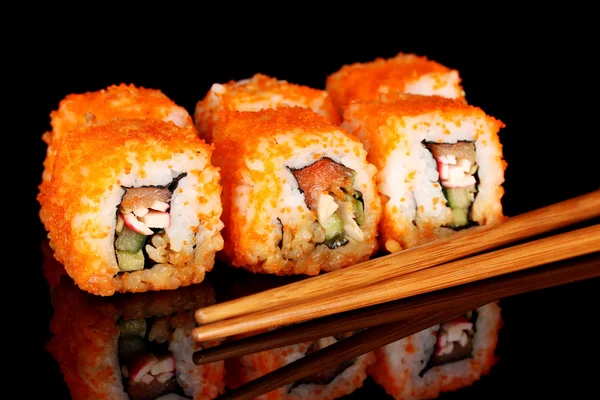 Вкусные суши и палочки для еды на черном фоне — стоковое фото