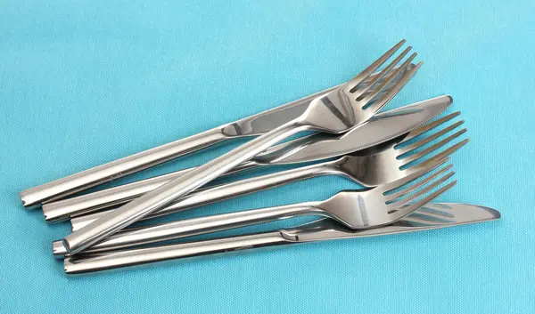 Tenedores y cuchillos sobre un mantel azul —  Fotos de Stock