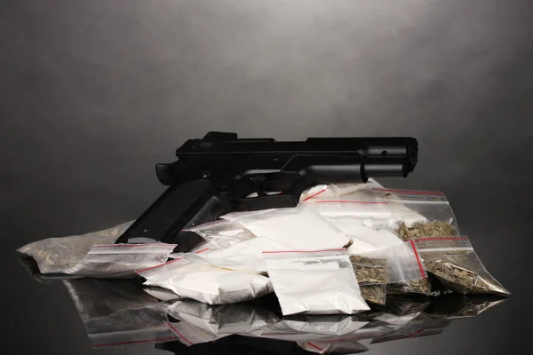Cocaina e marijuana in confezioni e pistola su sfondo grigio — Foto Stock