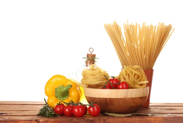 Spaghetti, noodles in bowl, jar of oil and vegetables on wooden table isola — Stock Photo, Image