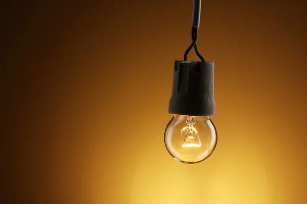 Uma lâmpada acesa no fundo amarelo — Fotografia de Stock