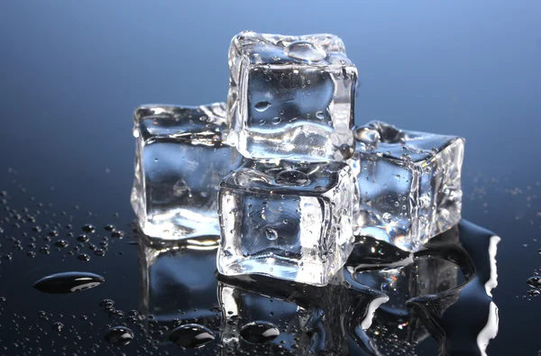 Таяние кубиков льда на синем фоне — стоковое фото