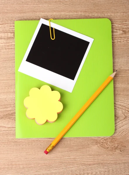 Papel fotográfico e caderno verde sobre fundo de madeira — Fotografia de Stock