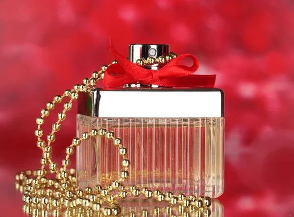 Frasco de perfume con lazo rojo sobre fondo rojo —  Fotos de Stock