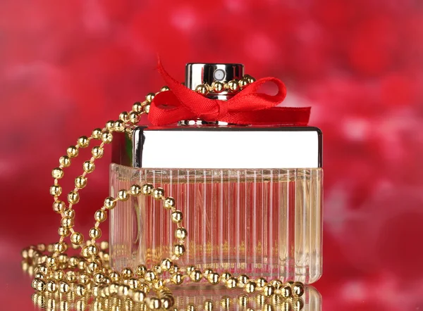 Perfume bottle with red bow on red background — Zdjęcie stockowe