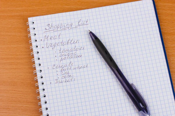 Shoping lijst en pen op houten tafel — Stockfoto