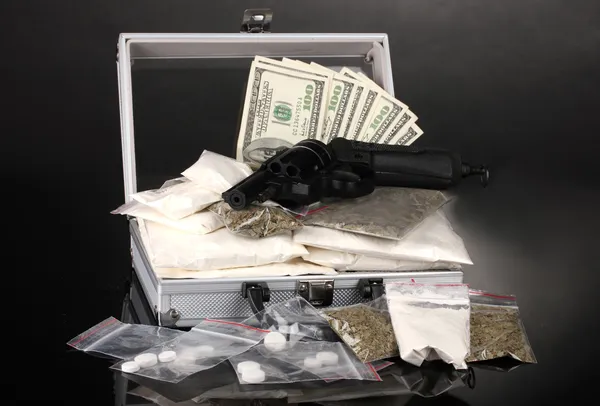 Cocaïne en marihuana met pistool in een koffer op grijze achtergrond — Stockfoto