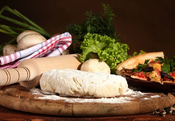 Leckerer Pizzateig, Gewürze und Gemüse auf Holztisch auf braunem Backblech — Stockfoto