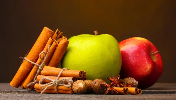 Varas de canela, maçãs noz-moscada e anis na mesa de madeira no fundo marrom — Fotografia de Stock