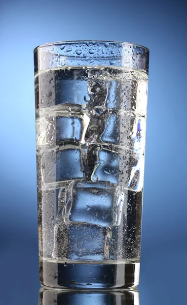Glass of water with ice on blue background