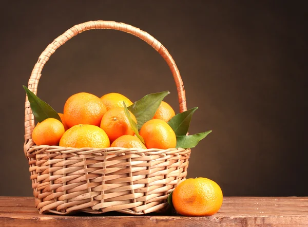 Tangerines in a beautiful basket on wooden table on brown background Stock Image
