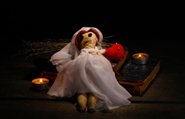 Voodoo doll girl-bride on a wooden table in the candlelight clipart