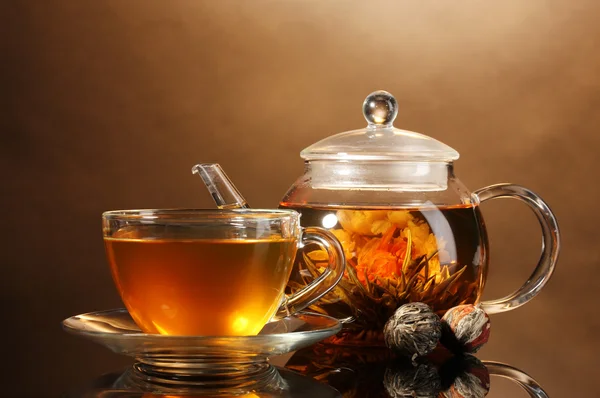 Glas Teekanne und Tasse mit exotischem grünem Tee auf Holztisch auf braunem Hintergrund — Stockfoto