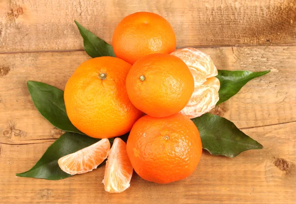 Tangerines with leaves on wooden table — Stock Photo, Image