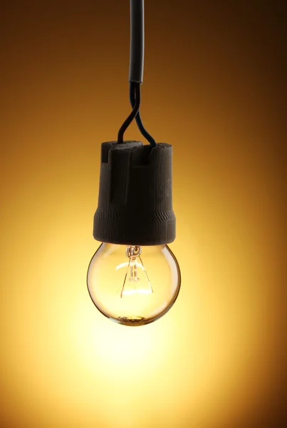Зажженная лампочка на желтом фоне — стоковое фото