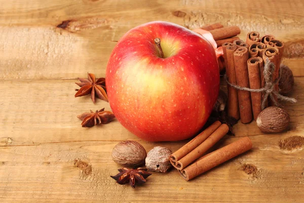 Bâtonnets de cannelle, pomme rouge, muscade et anis sur table en bois — Photo