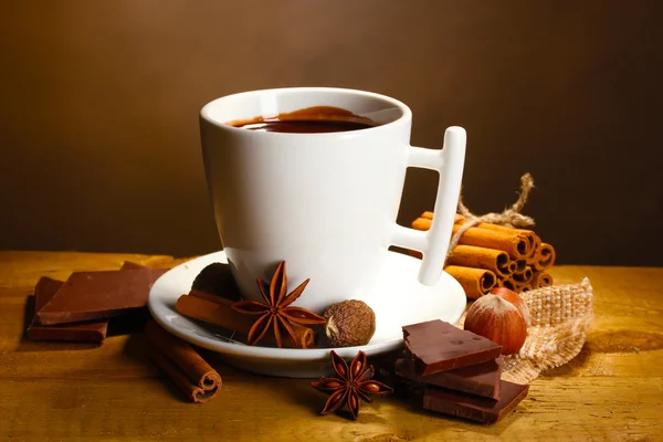 Kopje warme chocolademelk, kaneelstokjes, noten en chocolade op houten tafel o — Stockfoto