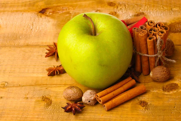 Bâtonnets de cannelle, pomme verte, muscade et anis sur table en bois — Photo