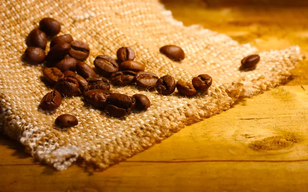 Grains de café sur sac sur table en bois — Photo