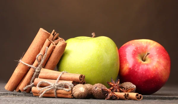 Kanelpinner, epler, muskatnøtt og anis på trebord med brun bakgrunn – stockfoto