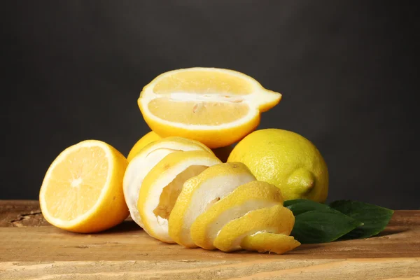 Zralých citronů s listy na dřevěný stůl na šedém pozadí — Stock fotografie