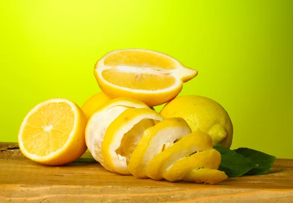 Rijp citroenen met bladeren op houten tafel op groene achtergrond — Stockfoto