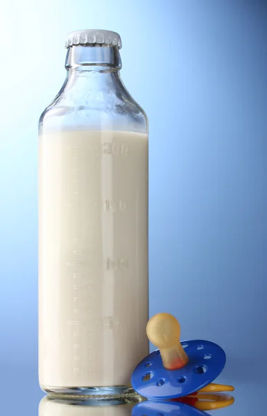 Garrafa de leite e chupeta em fundo azul — Fotografia de Stock