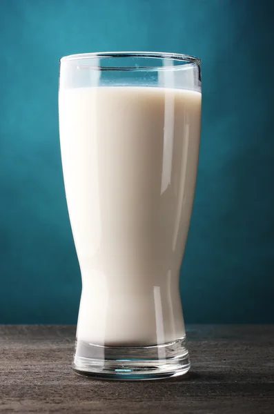 Glas Milch auf Holztisch auf blauem Hintergrund — Stockfoto