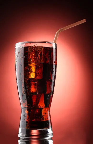 Glass of cola with ice on red background