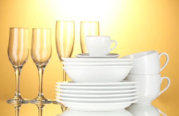 Tigelas vazias, pratos, copos e copos em fundo amarelo — Fotografia de Stock