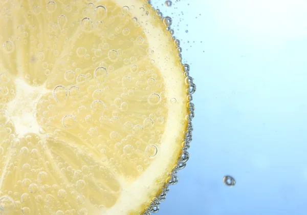 Tranche de citron dans l'eau bleue avec des bulles — Photo