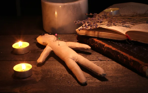 Muñeco vudú en una mesa de madera a la luz de las velas — Foto de Stock