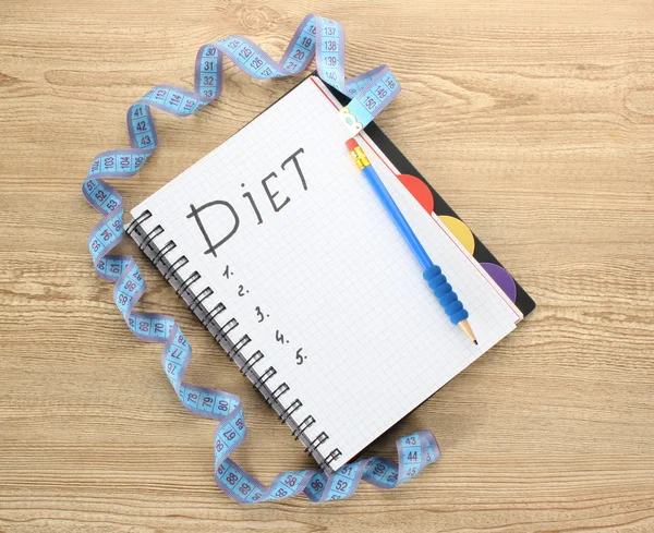 Planejamento da dieta. Caderno de fita métrica e caneta na mesa de madeira — Fotografia de Stock