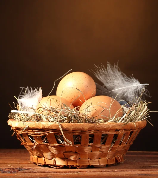 Яйца курицы и перепела в гнезде на деревянном столе на коричневом фоне — стоковое фото