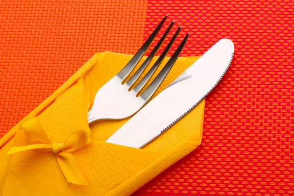Haarukka ja veitsi keltaisella liinalla jousella punaisella pöytäliinalla — kuvapankkivalokuva