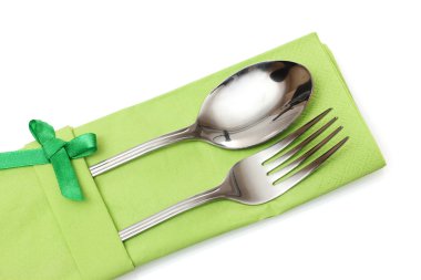 Fork and spoon in a green cloth with a bow isolated on white