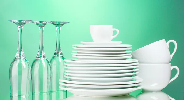 Чистые тарелки, чашки и стаканы на зеленом фоне — стоковое фото
