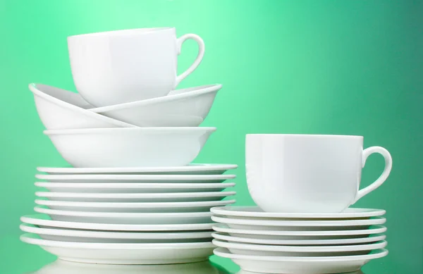 Чистые тарелки, чашки на зеленом фоне — стоковое фото